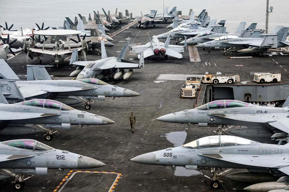 A US Navy officer walking past fighter jets parked on the flight deck of the Nimitz-class aircraft carrier USS Abraham during a media tour in Port Klang, on the outskirts of Kuala Lumpur, on Nov 26, 2024. 