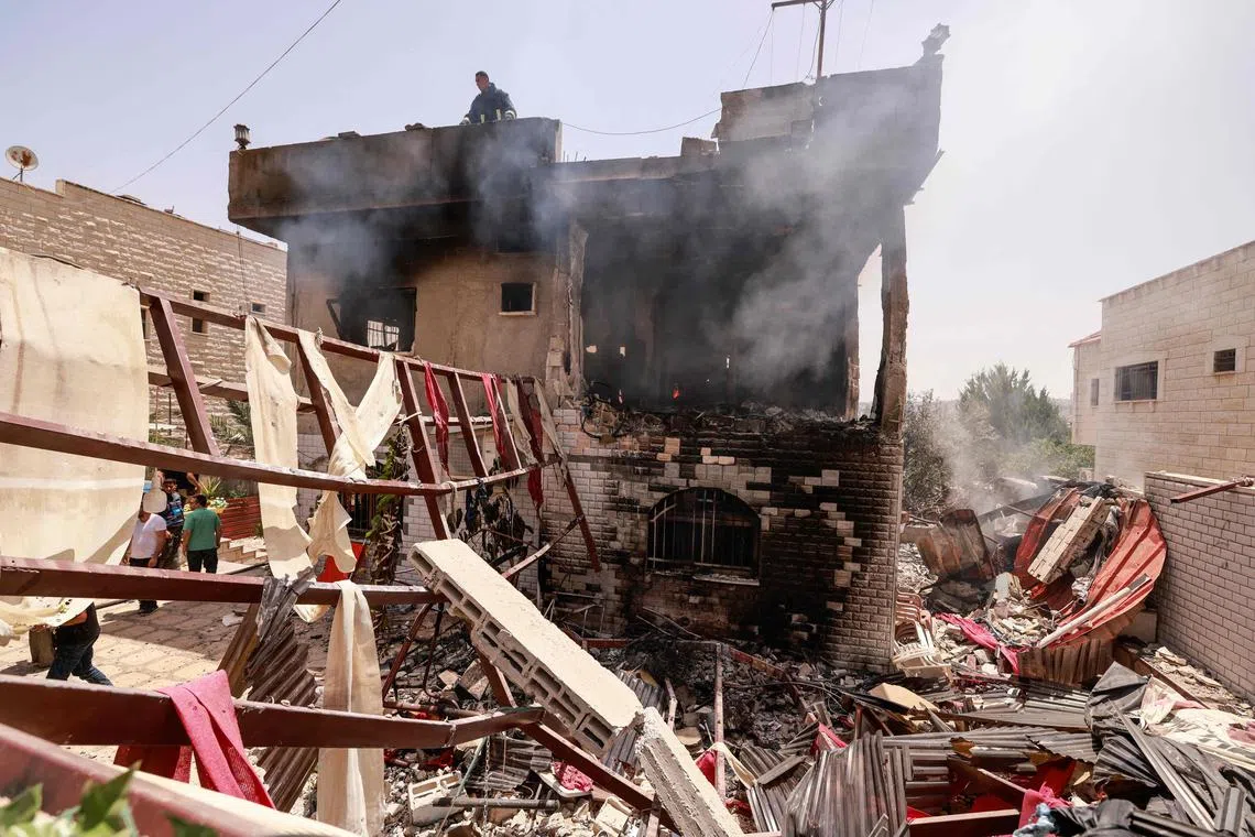 People and rescue workers assess the damage inflicted on a house during an Israeli raid in the occupied West Bank city of Jenin on July 5, 2024.