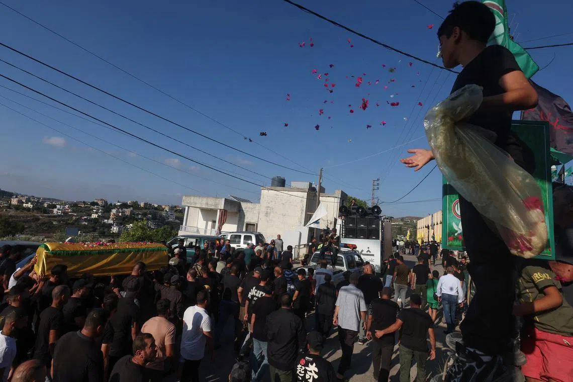 A child throws rose petals during the funeral of Wasila al-Haj Baydoun, who was killed by what security sources said was an Israel strike on Tuesday in Beirut southern suburbs, in Chehabiyeh, southern Lebanon July 31, 2024. REUTERS/Aziz Taher
