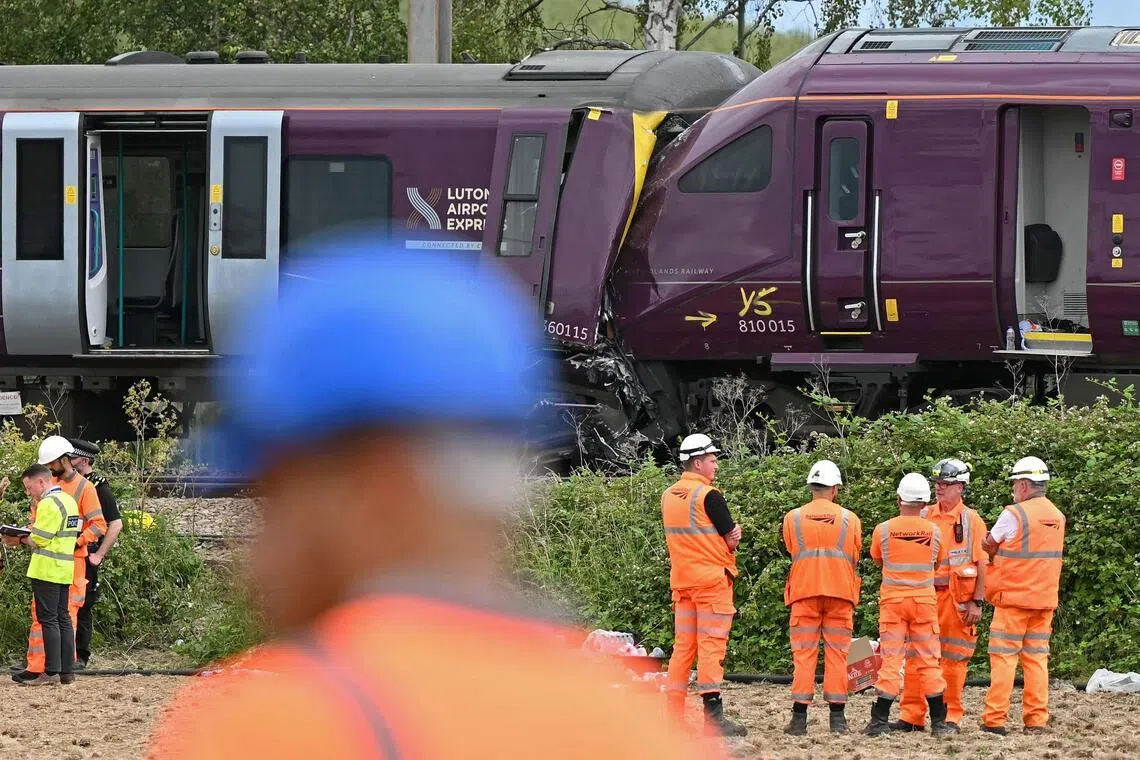 Rail and other officials working at the site of two trains which crashed into each other on June 19, south of Bedford in central England.