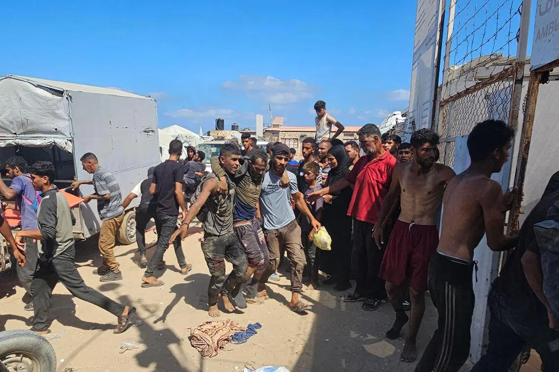 Palestinians helping an injured man reach a Red Cross clinic in Rafah, in the southern Gaza Strip, on July 12, after he was reportedly shot at an aid distribution point run by the US- and Israel-backed Gaza Humanitarian Foundation.