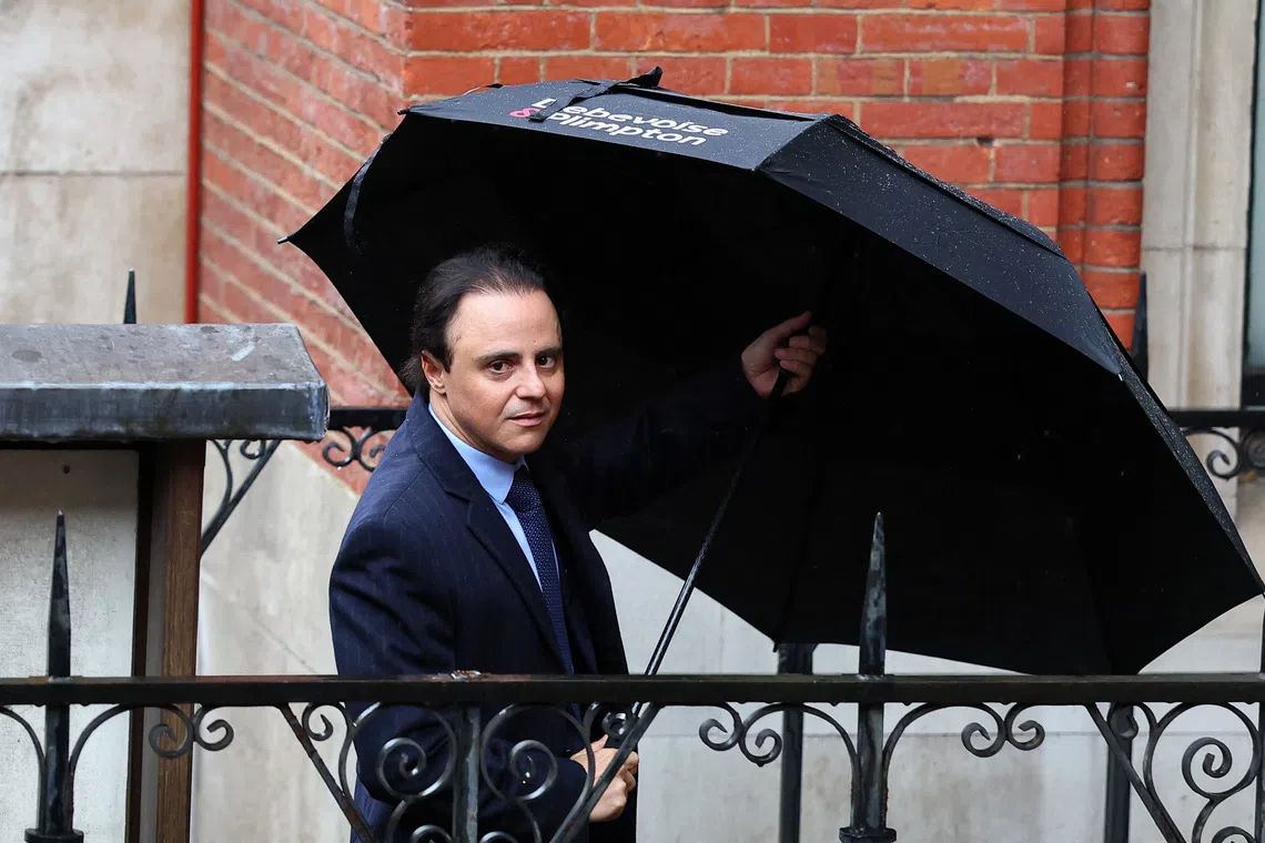 Former Ferrari Formula One driver Felipe Massa holds an umbrella near the High Court, where he is suing the governing FIA and former F1 chief Bernie Ecclestone, claiming he was the rightful 2008 world champion due to the Crashgate scandal at the Singapore Grand Prix and is seeking up to 64 million pounds in damages, in London, Britain, October 29, 2025. REUTERS/Isabel Infantes