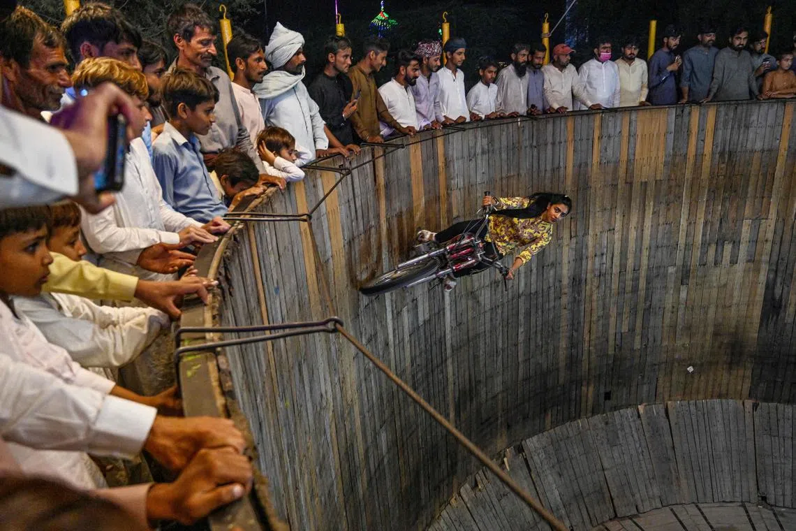 This photograph, released on May 29, 2024 shows Fatima Noor, a stunt girl, performing in a 'Wall of Death' during an annual mela or carnival at a Sufi shrine in Shah Jiwana, a town in the Jhang district of Pakistan's Punjab province.