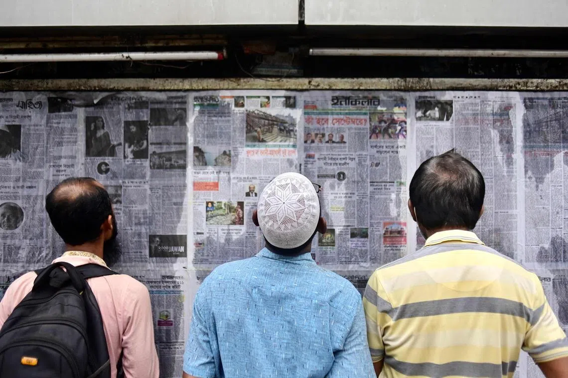 In this photograph taken on September 1, 2023, pedestrians read Bangladesh's local newspapers displayed along a street in Dhaka. Hundreds of articles praising Bangladeshi government policies apparently by independent experts have appeared in national and international media but the authors have questionable credentials, fake photos and may not even exist, an AFP investigation has found. (Photo by Munir UZ ZAMAN / AFP) / TO GO WITH: Bangladesh-Politics-Disinformation-Media, INVESTIGATION by Qadaruddin SHISHIR
