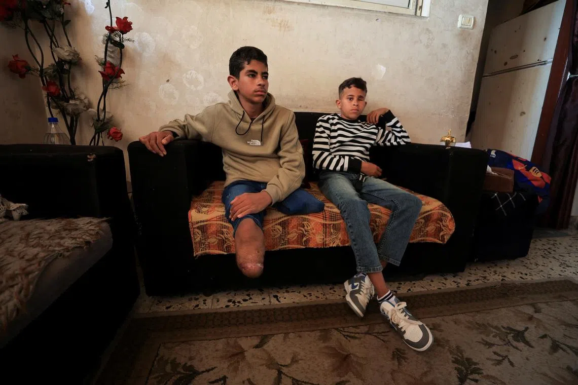Fadel Al-Naji, 14, who lost both legs, sits beside his brother Amir Al-Naji, 11, who lost an eye, after they were injured in an Israeli strike, at their home in Gaza City, April 10, 2026.