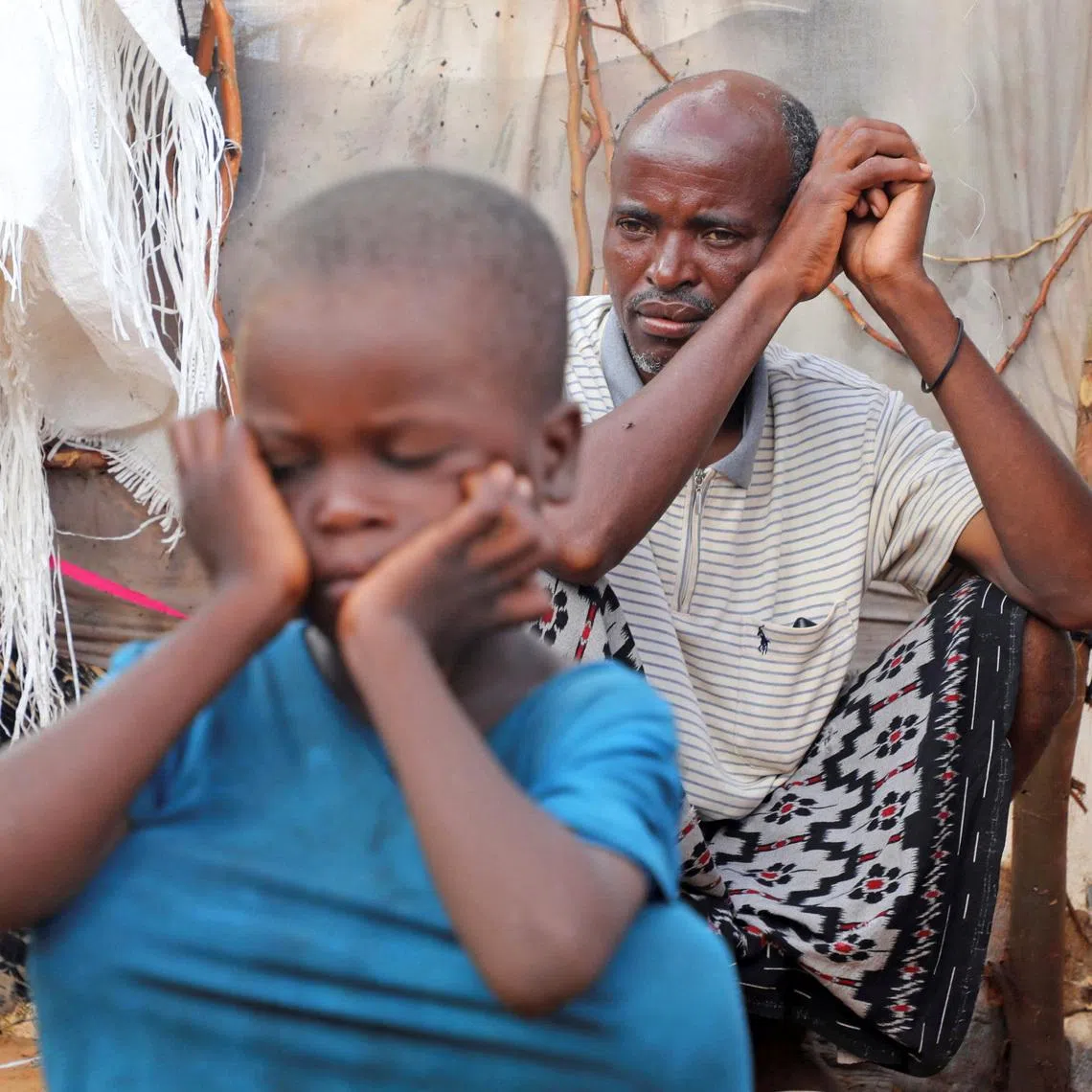 Internally displaced people sit outside their makeshift shelters during a visit by World Food Programme’s Assistant Executive Director for Programme Operations, Matthew Hollingworth (not in the photo), to assess the knock on effects from the escalation in the Middle East, alongside drought and sharp cuts in humanitarian funding that are worsening hunger, in Kahda district of Mogadishu, Somalia May 7, 2026. REUTERS/Feisal Omar