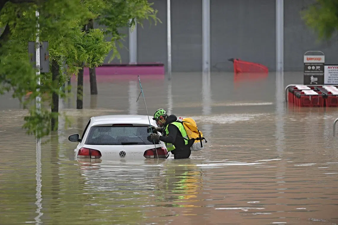 A speleological alpine rescuer looks in a car for missing persons near a supermarket in a flooded area in Cesena on May 17, 2023. 