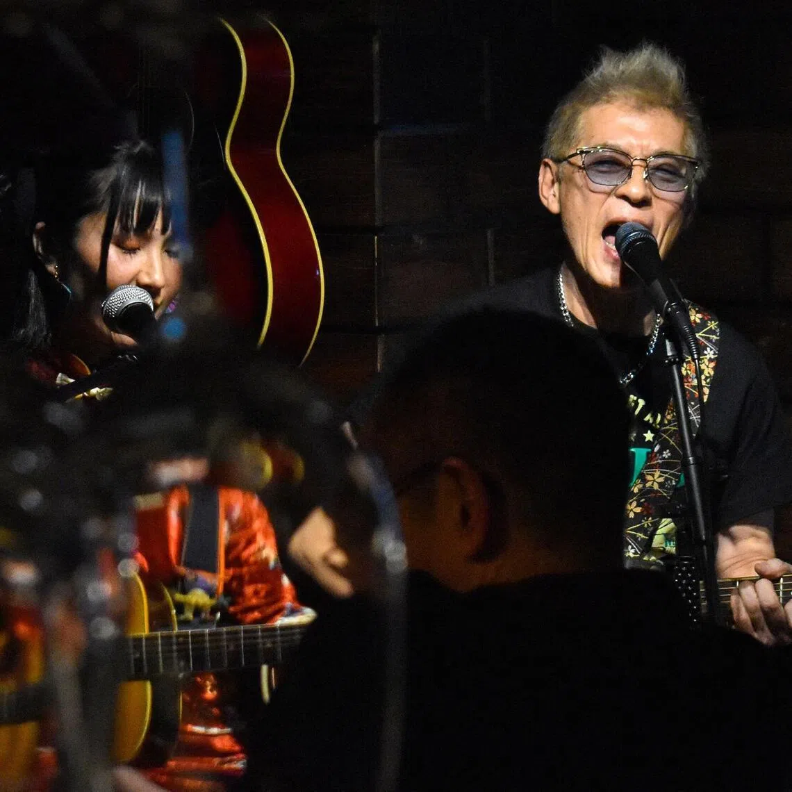 Lawyer Akihiro Shima, who spearheads a landmark climate change lawsuit in Japan, singing alongside Yuko Nakano at a bar in Tokyo's Ginza district. 
