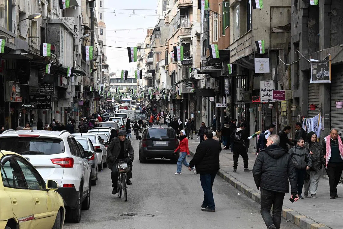People walk past shops in Homs on Feb 10, 2025.