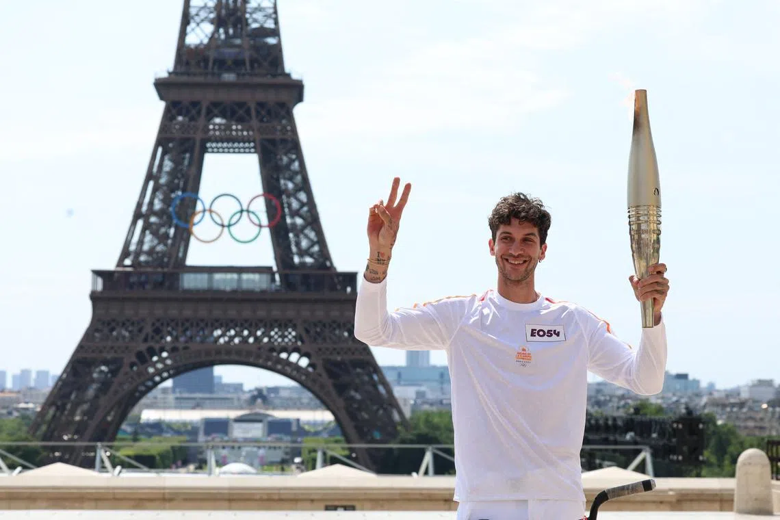 French BMX world champion Matthias Dandois holding the Olympic flame in front of the Eiffel Tower during the Olympic torch relay in Paris on July 15.
