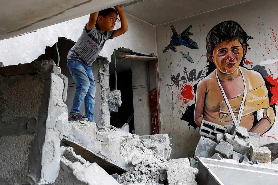 A Palestinian boy stands inside a house destroyed in an Israeli strike in the recent Gaza-Israel fighting, in Deir Al-Balah, central Gaza Strip, June 8.