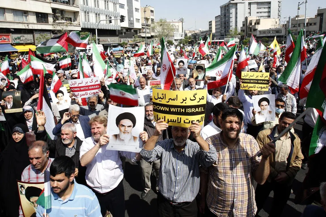 epa11288248 Iranians carrying placards and portraits of the Iranian supreme leader Ayatollah Ali Khamenei and former supreme leader Ruhollah Khomeini wave Iranian and Palestinian flags during an anti-Israel rally in Tehran, Iran, 19 April 2024. Iranian state media reported that three aerial objects were destroyed by air defense systems over the central city of Isfahan early morning on 19 April. The explosions come after a drone and missile attack carried by Iran's Islamic Revolutionary Guards Corps (IRGC) towards Israel on 13 April, following an airstrike on the Iranian embassy in Syria which Iran claimed was conducted by Israel.  EPA-EFE/ABEDIN TAHERKENAREH