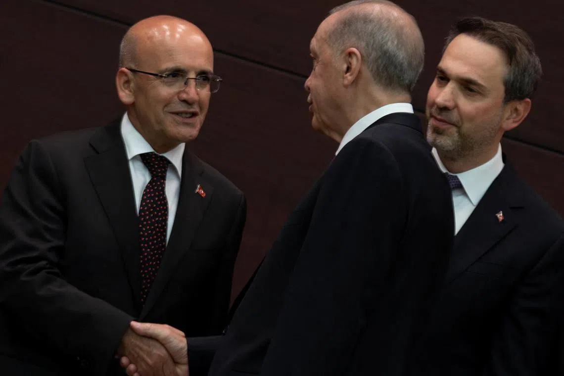 Turkish President Tayyip Erdogan (centre) shakes hands with Finance Minister Mehmet Simsek, flanked by new Energy Minister Alparslan Bayraktar.
