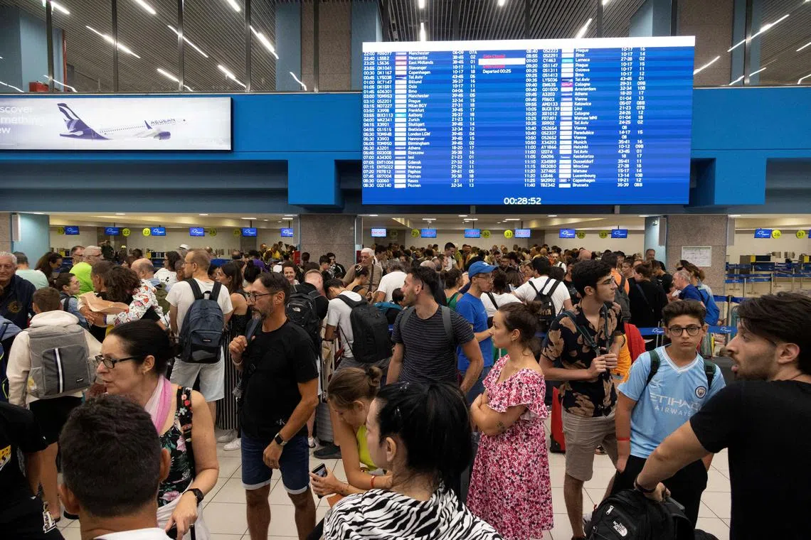 Tourists wait for departing planes at the airport, after being evacuated following a wildfire on the island of Rhodes.