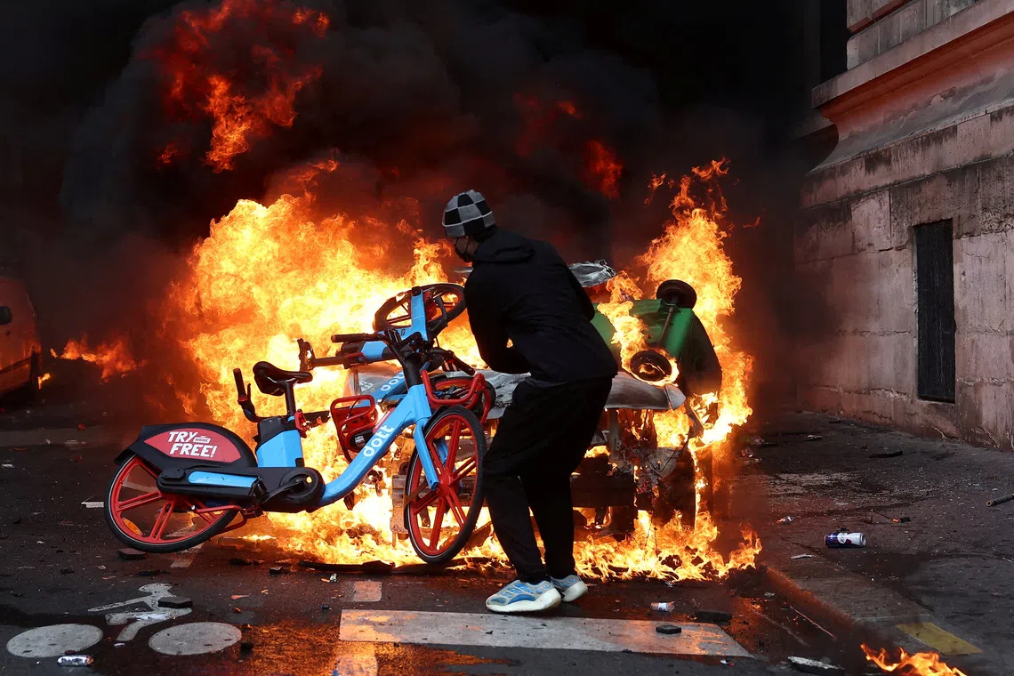 FILE PHOTO: A protester throws a bicycle onto a burning car amid clashes during a day of demonstrations against the cost of living and rising fuel prices in Paris as part of nationwide protests called by the \"Yellow Vests\" movement, joined by French high school and university students, teachers and parents demanding better school conditions and government action, as well as labour unions, workers, farmers and retirees, France, October 17, 2026.   REUTERS/Abdul Saboor/File Photo