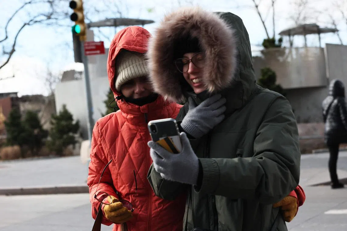 People bundle up as they shield themselves from cold winds, in New York City.