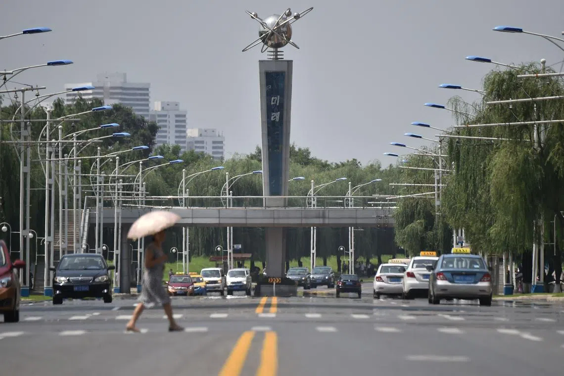 A pedestrian uses an umbrella to provide shade from the sun while walking across the Mirae Scientists Street in Pyongyang on August 13, 2024. (Photo by KIM Won Jin / AFP)