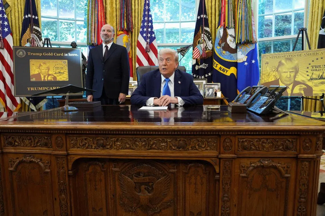 US President Donald Trump speaking as he sits next to a sign that reads "Trump Gold Card is here", with US Secretary of Commerce Howard Lutnick standing by his side in the Oval Office on Sept 19. 
