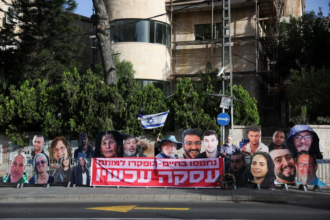 A woman holds an Israeli flag near the posters of hostages, killed during the deadly October 7 attack by Palestinian Islamist group Hamas or while being held hostage in Gaza, outside the Prime Minister's residence in Jerusalem May 23, 2024. REUTERS/Ronen Zvulun/ File Photo