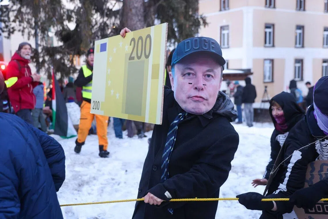 A protester wears a mask with the image of billionaire Elon Musk, whose wealth grew five times more in 2025 than at the end of 2022.
