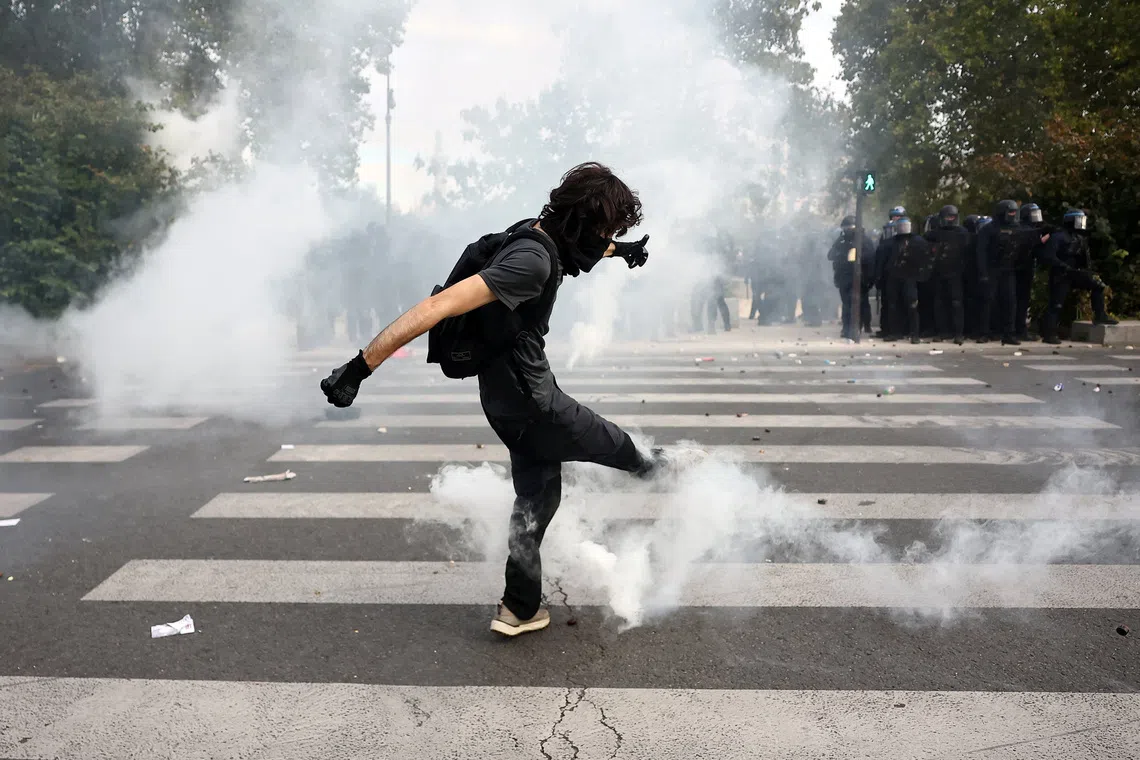 A masked student kicking a tear gas canister in France on Oct 6, as nationwide protests over decrepit conditions in French high schools descended into sporadic violence.
