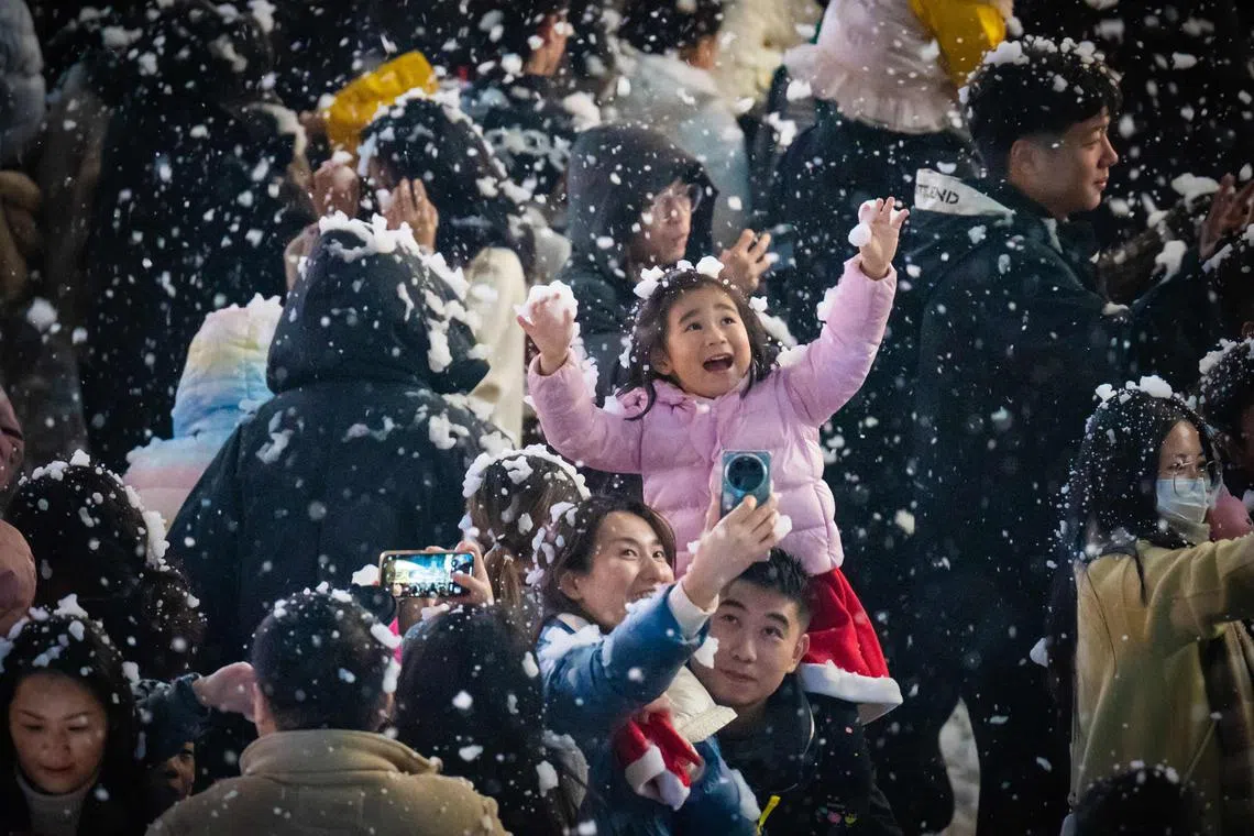 A child playing with artificial snow at a business area in China's southwestern Chongqing municipality on Dec 24, 2023.