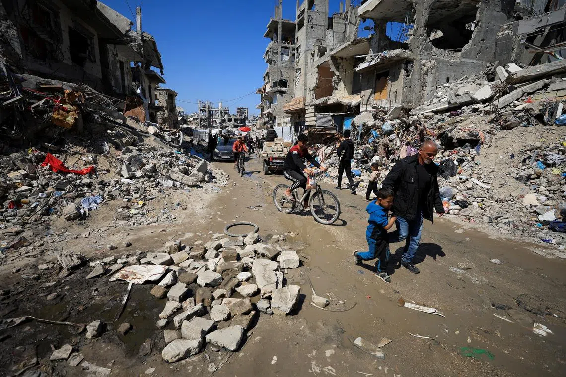 Palestinians pass by the rubble of destroyed houses, in Gaza City on March 11.