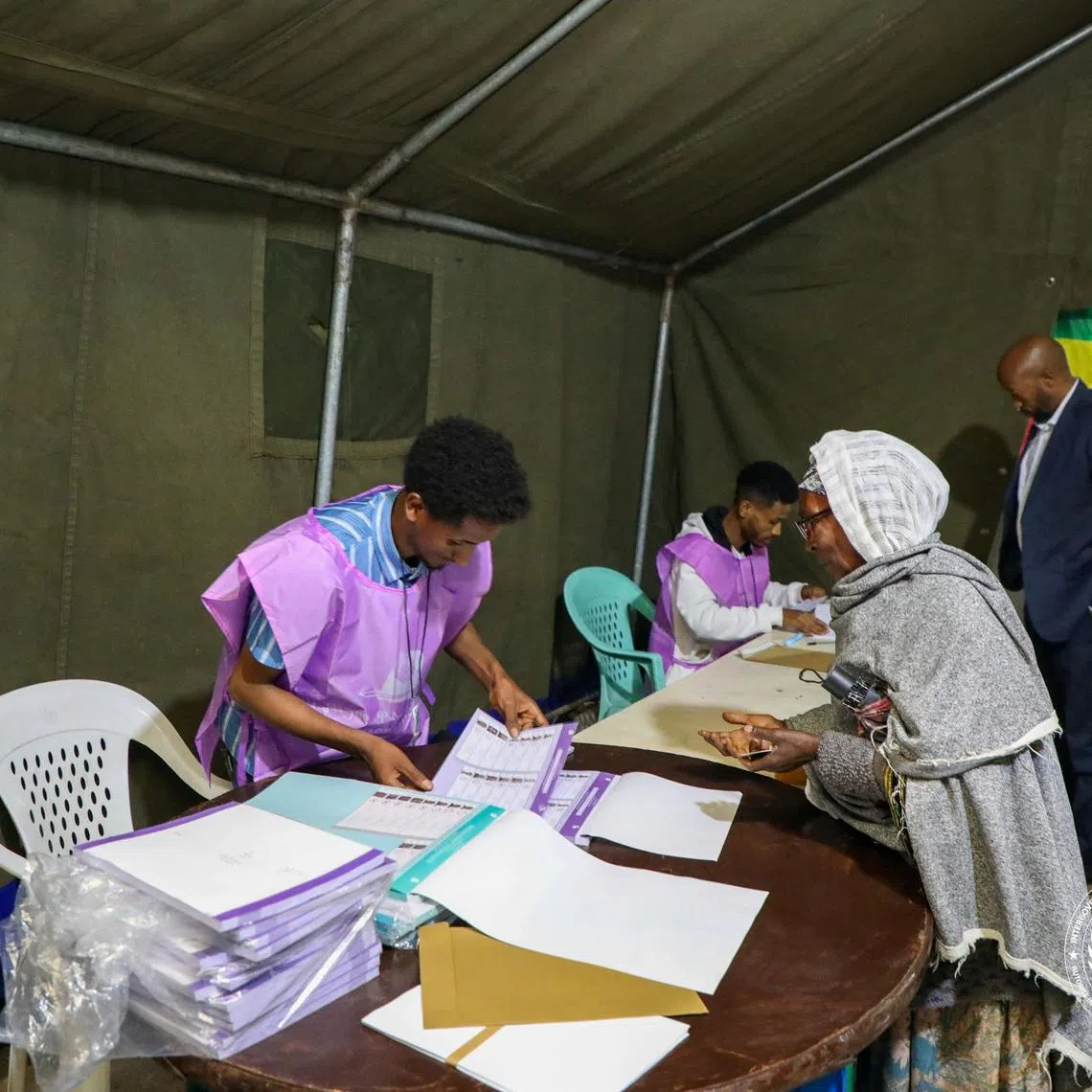 National Election Board of Ethiopia (NEBE) officials process a voter before casting her ballot at a polling station during the parliamentary and regional elections in Addis Ababa, Ethiopia, June 1, 2026. The Intergovernmental Authority on Development (IGAD)/Handout via REUTERS
