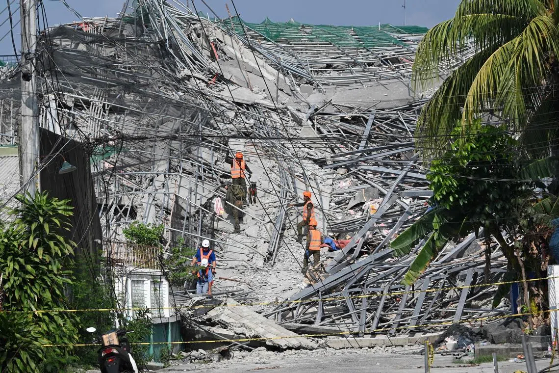 Military personnel with a working dog conduct search and rescue operations at a collapsed building in Angeles City, Pampanga province, north of Manila, on May 25.