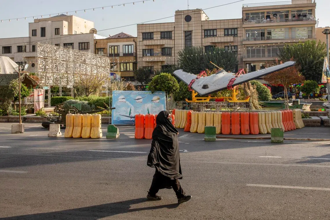 A woman walks past an Iranian Shahed drone variant displayed at a military exhibit in Tehran, Iran, on Oct 1, 2025.