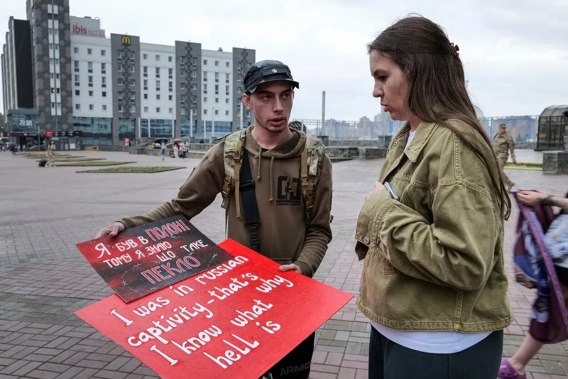 Svitlana Bilous, a 34-year-old civic activist and the wife of a Ukrainian soldier missing in action, and Illia Illiashenko, a Ukrainian former prisoner of war who was captured by Russian forces in Mariupol in 2022, look at posters before their bus tour to Switzerland to advocate for Ukrainian soldiers in Russian captivity, amid Russia's attack on Ukraine, in Kyiv, Ukraine June 12, 2024. REUTERS/Charlotte Bruneau