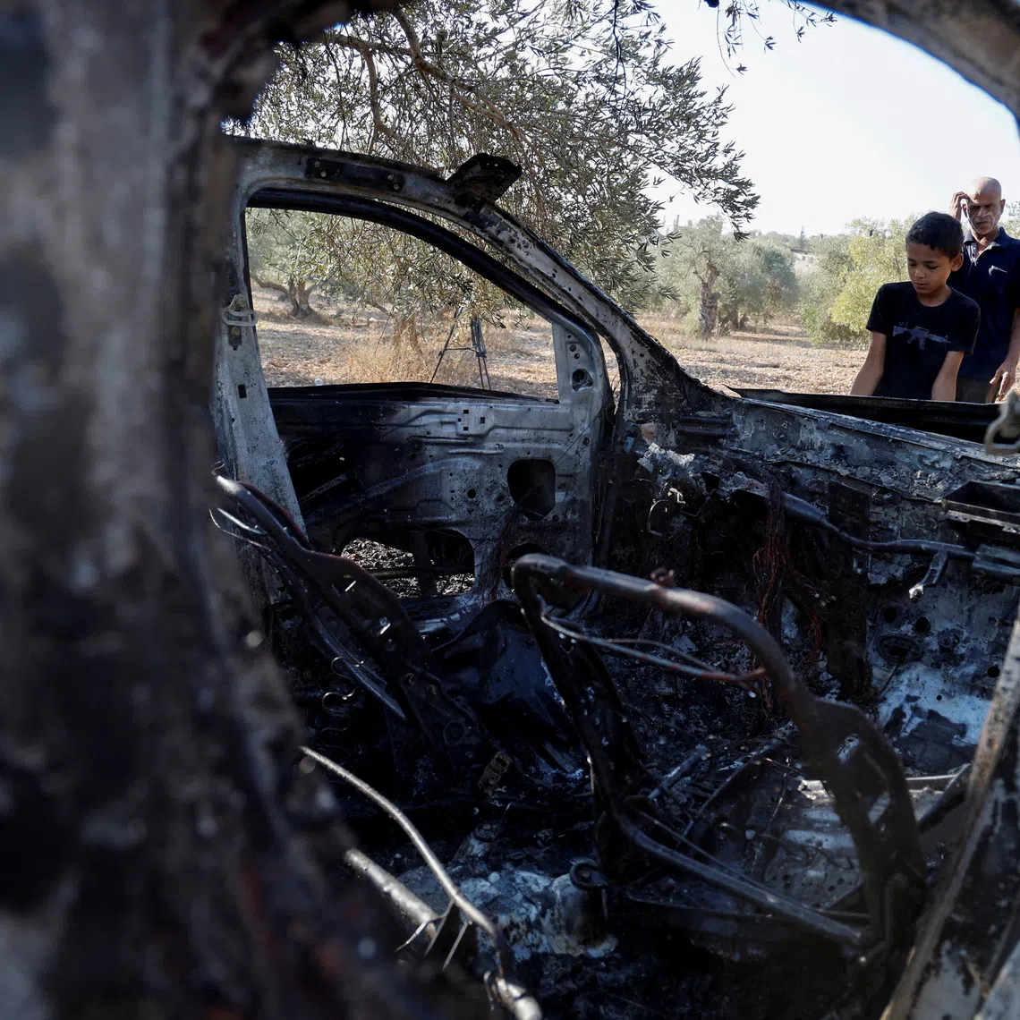 People inspect a burnt vehicle at the site where Israeli forces killed three Palestinians, near Jenin, in the Israeli occupied West Bank October 28, 2025. REUTERS/Raneen Sawafta