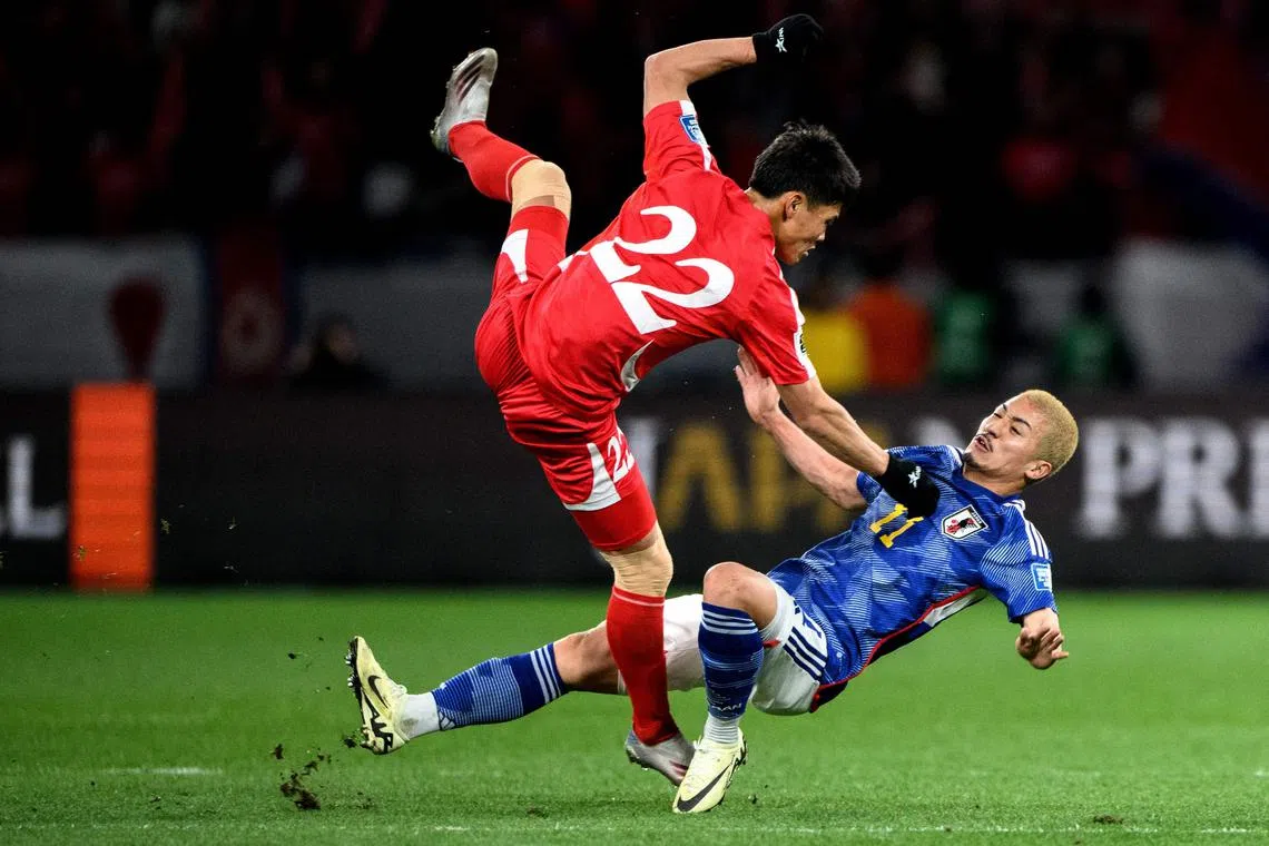 North Korea's Kim Kuk Bom clashes with Japan's Daizen Maeda during their World Cup qualifier in Tokyo on March 21.