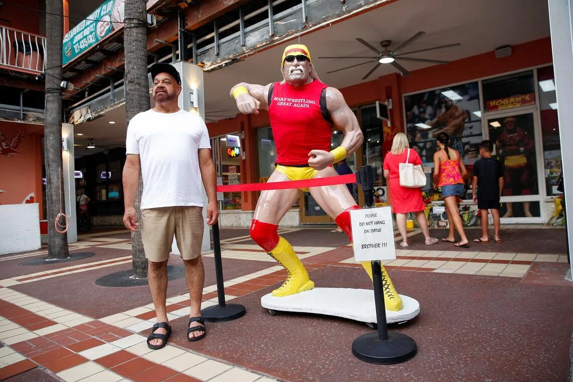 A fan posing beside a life-size Hulk Hogan statue in front of Hogan's Beach Shop in Florida, on Aug 1.
