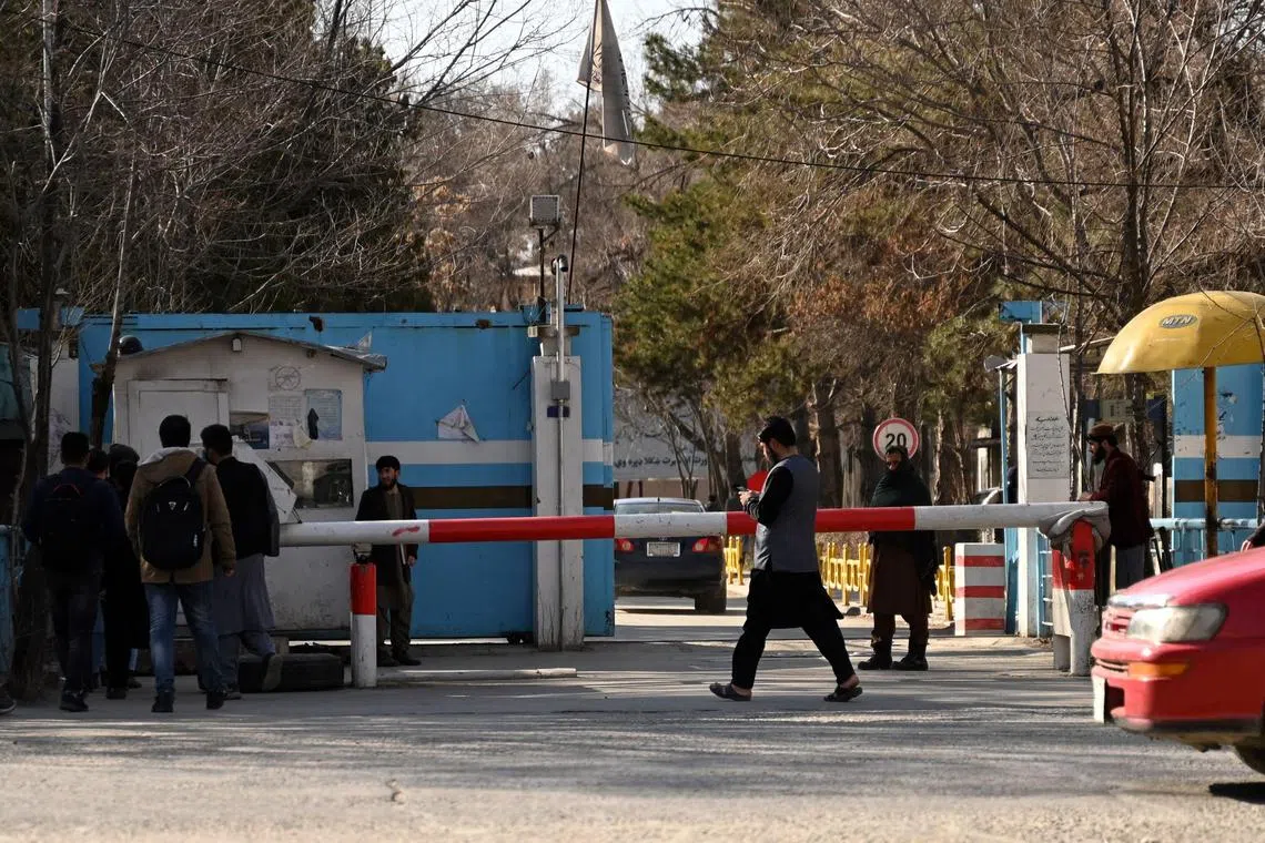 Taliban security personnel stands guard as male students arrive after the re-opening of the Kabul University at its entrance gate in Kabul on March 6, 2023.