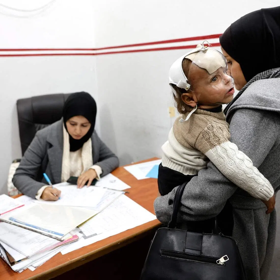 A Palestinian woman with a child speaks to a member of staff at the Doctors Without Borders clinic, in the al-Rimal neighbourhood of Gaza City, on Dec 31.