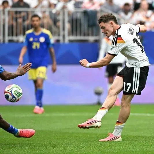 Germany's midfielder Florian Wirtz (right) kicks the ball in front of Curacao's midfielder Leandro Bacuna during the match at the Houston Stadium in Houston, tEXAS.