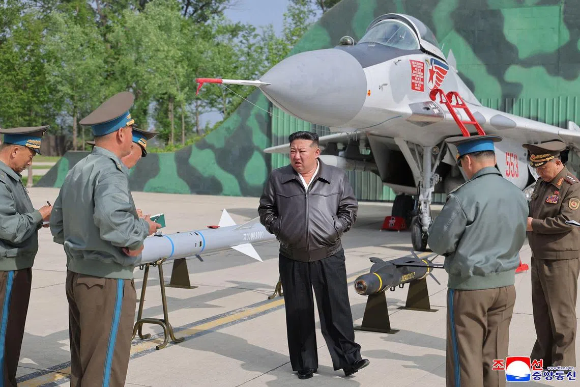 This picture taken on May 15 and released from North Korea's official Korean Central News Agency (KCNA) on May 17 shows North Korean leader Kim Jong Un (centre) beside a MiG-29 aircraft. 