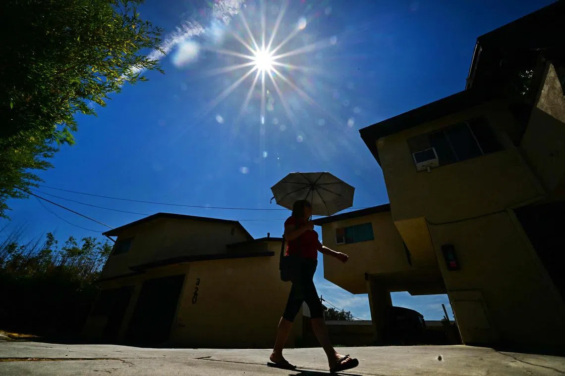 A woman shielding herself from the hot sun with an umbrella in Alhambra, California, on Aug 20.