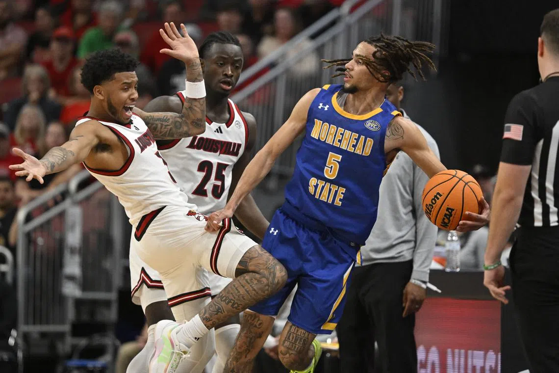 FILE PHOTO: Nov 4, 2024; Louisville, Kentucky, USA;  Morehead State Eagles guard Tyler Brelsford (5) looks to pass under the pressure of Louisville Cardinals guard Koren Johnson (3) and forward Aboubacar Traore (25) during the second half at KFC Yum! Center.  Mandatory Credit: Jamie Rhodes-Imagn Images/File Photo