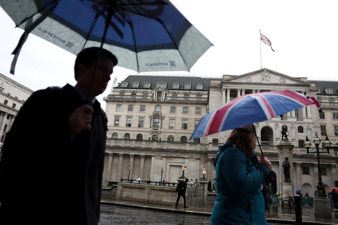 FILE PHOTO: A tourist shelters from the rain under an Union Jack umbrella near the Bank of England in the City of London financial district in London, Britain, February 13, 2024. REUTERS/Isabel Infantes/File Photo