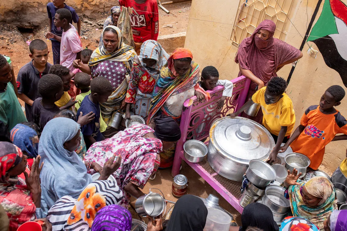 FILE PHOTO: Sudanese women from community kitchens run by local volunteers distribute meals for people who are affected by conflict and extreme hunger and are out of reach of international aid efforts, in Omdurman, Sudan, July 27, 2024. REUTERS/Mazin Alrasheed/File Photo