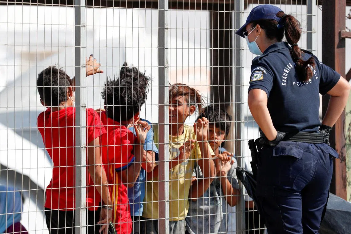 A photo from Sept 20, 2020, shows a police officer talking to children inside a temporary camp for migrants and refugees, in Lesbos, Greece. 