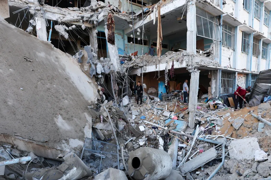 Palestinians inspect the site of an Israeli strike on an UNRWA school sheltering displaced people, in the Bureij camp in the central Gaza Strip, May 7, 2025. REUTERS/Ramadan Abed