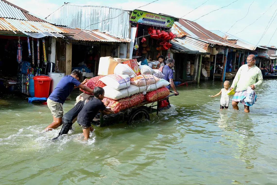 People push a handcart carrying supplies through the flood.