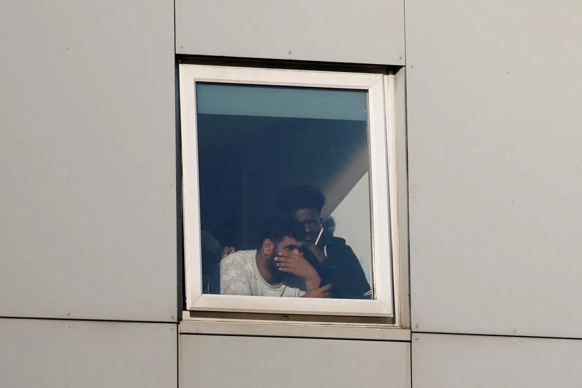 FILE PHOTO: Asylum seekers react as they look out the window at the Cresta Court hotel, as people take part in an anti-immigration demonstration outside the hotel, in Altrincham, Britain, August 8, 2025. REUTERS/Phil Noble/File Photo
