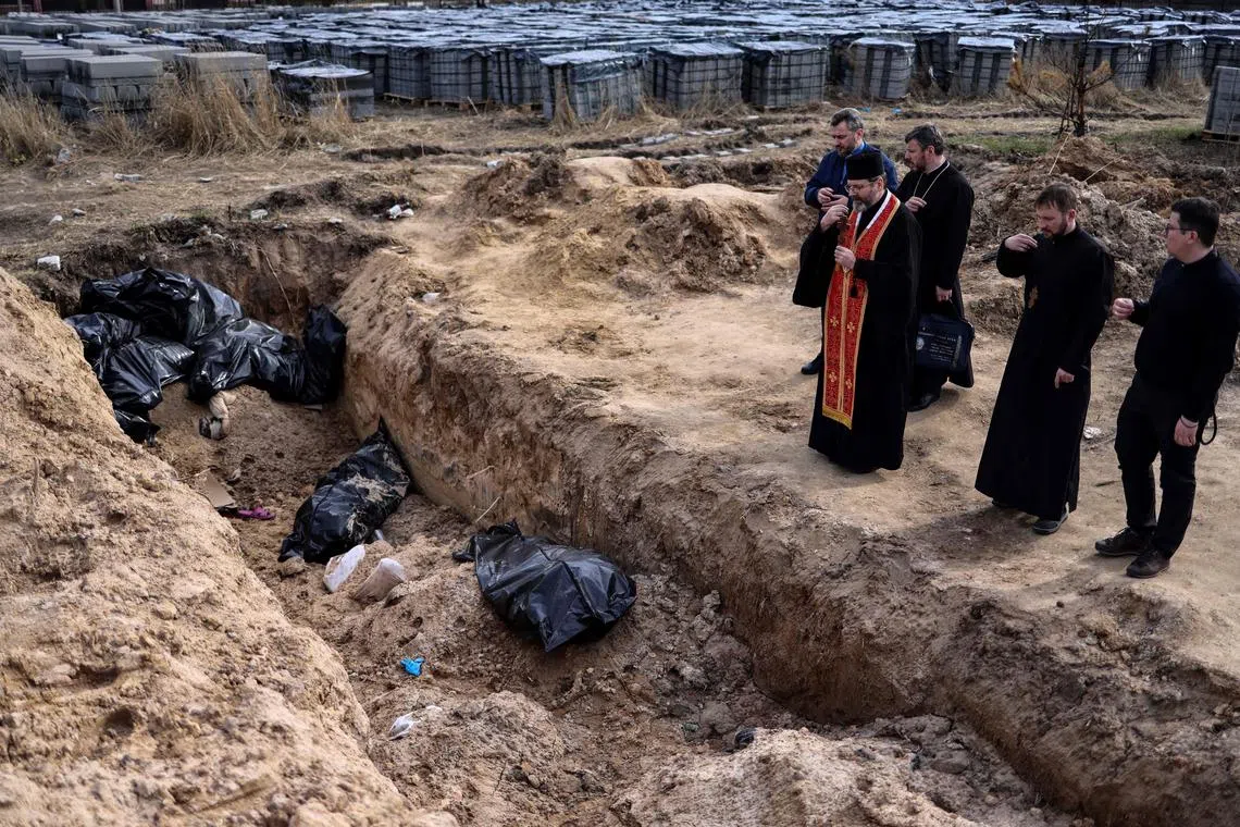 Priests pray by body bags in a mass grave in Bucha, where Russian forces were said to have committed atrocities on civilians.