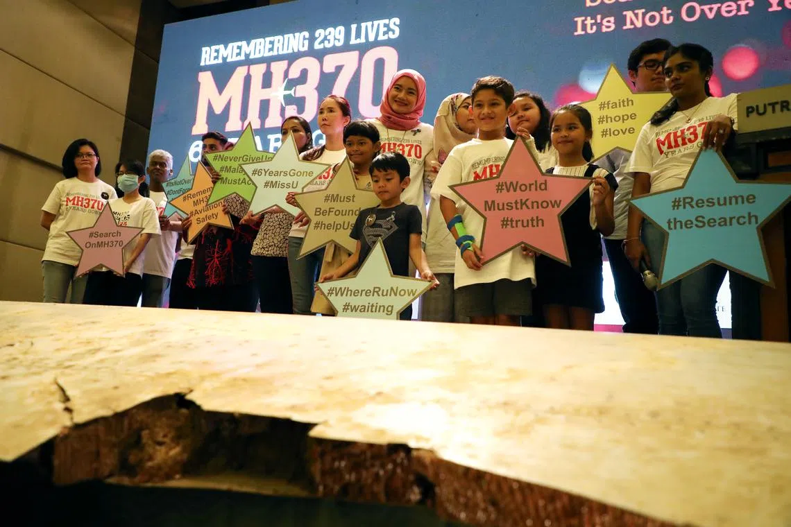 FILE PHOTO: Family members of the victims pose for a group picture with a debris of the missing Malaysia Airlines flight MH370 in Putrajaya, Malaysia, March 7, 2020. REUTERS/Lim Huey Teng
