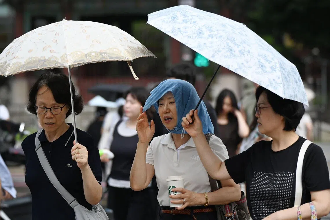 People shelter from the heat under umbrellas in Seoul.