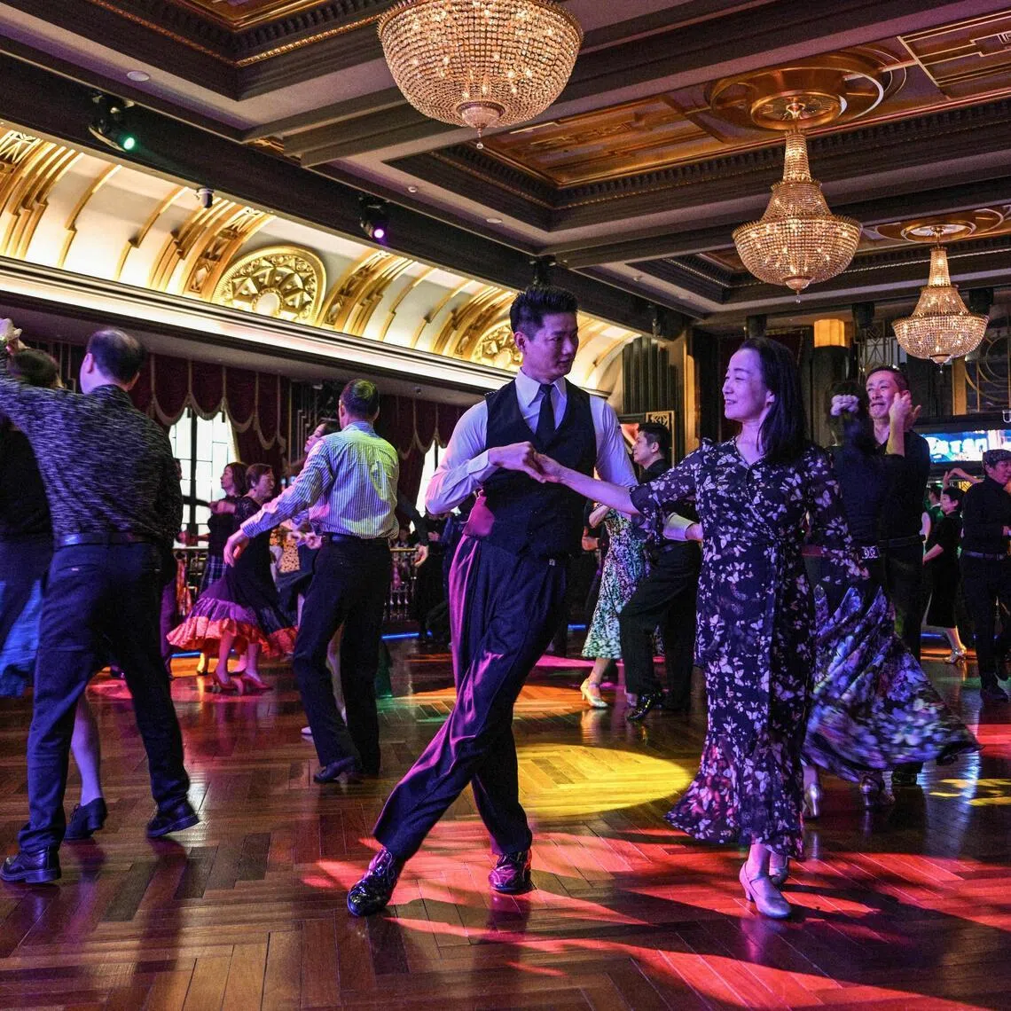 TOPSHOT - This photo taken on December 11, 2025 shows couples dancing at the Paramount Ballroom in the Jing'An district of Shanghai. It was just a regular Wednesday at a lunchtime dance club in Shanghai, where dance hall culture has been deeply rooted in the city's identity since its jazz-age heyday. On any given day, multiple venues host hours-long daytime sessions across the finance hub, some starting as early as 6 am. Establishments like the historic Paramount Ballroom are time capsules from the 1930s, while others flash with neon pink and green rave lights in the early afternoon. (Photo by Hector RETAMAL / AFP) / To go with 'CHINA-LIFESTYLE-DANCE-HISTORY-DEMOGRAPHICS, REPORTAGE' by Rita QIAN